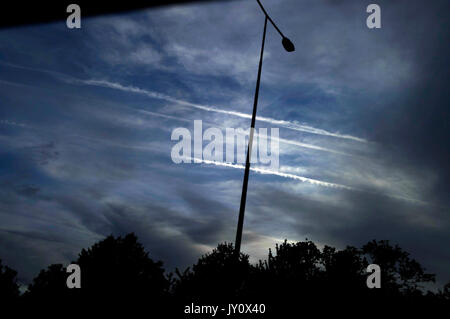 Contrails aereo nel cielo sopra la silhouette della lampada luce post Foto Stock