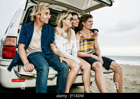 Caucasian amici seduti in auto berlina a beach Foto Stock