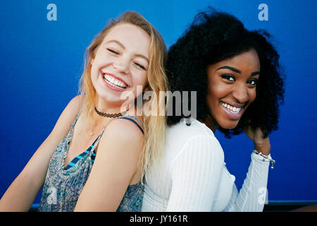 Gli amici seduti vicino alla parete blu ridere Foto Stock