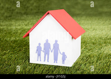 Close-up del modello di casa con la famiglia su di esso sul campo erboso Foto Stock