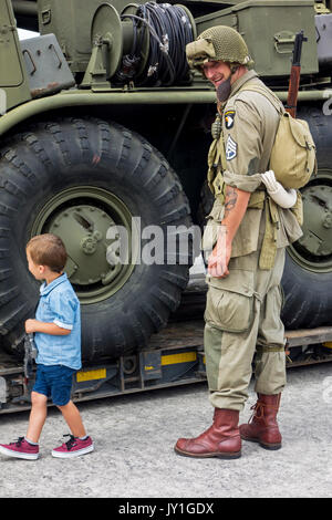 Ragazzino con pistola giocattolo e WW2 reenactor in US soldier outfit guardando il missile carrello a seconda guerra mondiale militaria fair Foto Stock