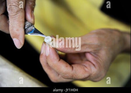 Vista dettagliata del lavoratore con le mani in mano il carving un dettaglio in plastica Foto Stock