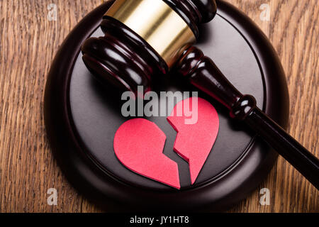 Rosso cuore spezzato sul martello di legno a scrivania in legno Foto Stock
