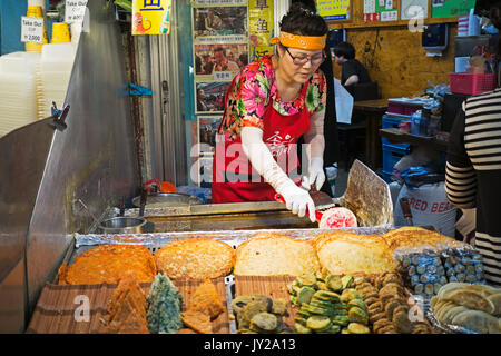 Seoul, Corea del Sud - Aprile 08, 2017: Donna venditore prepara uno spuntino al mercato Gwangjang in Seoul. Si tratta di uno degli ultimi posti per sperimentare la tradizionale Foto Stock