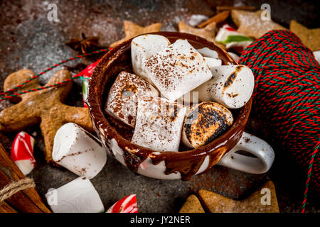 Anno nuovo, dolcetti di Natale, dolci. Tazza di cioccolata calda con marshmallow fritto, ginger star cookies, uomini di panpepato, striped candy, spezie cannella Foto Stock