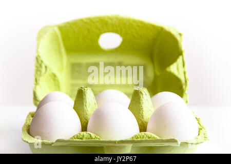Sei uova di colore bianco in un aperto il pacchetto verde, visto dall'alto/laterale, contro uno sfondo bianco closeup. Foto Stock