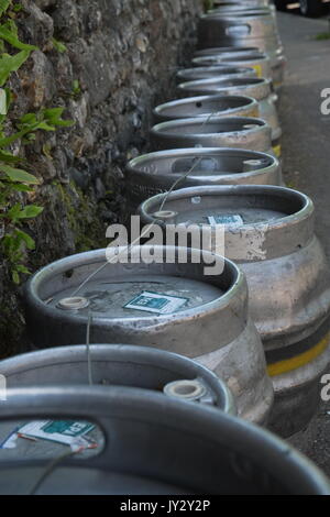 Barili di birra in una linea di raccolta attendono accanto a una parete al di fuori di un pub Foto Stock