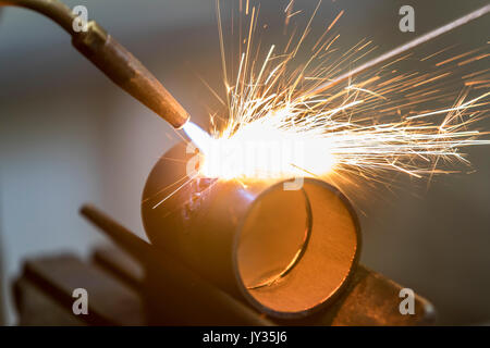 La saldatura, con una torcia di saldatura di due tubi di metallo vengono saldate, seminario di formazione per riscaldamento e idraulici artigiani, Foto Stock