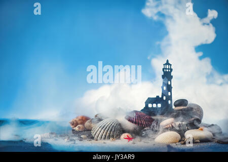 Mare concettuale a tema shot con piccolo faro su un mucchio di sabbia e conchiglie su uno sfondo blu. Copia dello spazio. Foto Stock