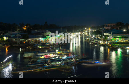 Alba sul mercato galleggiante con segnale di occupato di notte le luci di barche sfavillìo di trasportare beni agricoli al commercio in preparazione per il nuovo anno lunare in Soc Tran Foto Stock