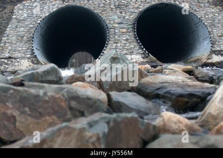 Canale sotterraneo - scarico sotto la strada per il piccolo fiume. Grosso tubo sotto l'AUTOSTRADA, AUTOSTRADA ingegneria; roadmaking. Doppio scarico. In corrispondenza dell'altra estremità del tubo di legno visibile Foto Stock