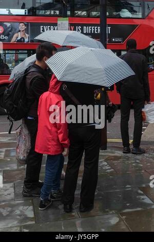 Londra, Regno Unito. 18 Agosto, 2017. I turisti in Piccadilly Circus catturati in una luce doccia a pioggia a Londra. Credito: claire doherty/Alamy Live News Foto Stock