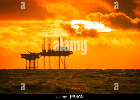 Southport, Merseyside, 18 agosto 2017. Regno Unito Meteo. Dopo una giornata di sole oltre il nord-ovest dell'Inghilterra, un tramonto mozzafiato si accoccola nell'orizzonte dietro il Hamilton oil rig off il Southport costa. Il complesso di Douglas è un 54 metri (177 ft) alta sistema di tre piattaforme collegate nel mare d' Irlanda, 24 chilometri al largo della costa del nord del Galles. Il Douglas campo petrolifero è stato scoperto nel 1990, e la produzione è iniziata nel 1996. Sistemazione Questo modulo è stato precedentemente noto come la fiamma di Morecambe jack-up impianto di perforazione. Credito: Cernan Elias/Alamy Live News Foto Stock