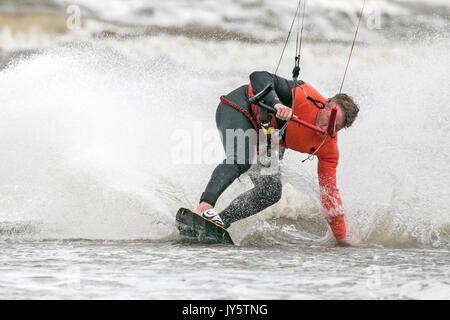 Southport, Merseyside, 19 agosto 2017. Regno Unito Meteo. Davvero un ventoso e molto più freddo giorno con alcuni pesanti Scattered Showers non scoraggiare questo kite boarder da equitazione il surf sulla marea a Southport nel Merseyside. Credito: Cernan Elias/Alamy Live News Foto Stock