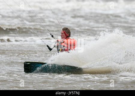 Southport, Merseyside, 19 agosto 2017. Regno Unito Meteo. Davvero un ventoso e molto più freddo giorno con alcuni pesanti Scattered Showers non scoraggiare questo kite boarder da equitazione il surf sulla marea a Southport nel Merseyside. Credito: Cernan Elias/Alamy Live News Foto Stock