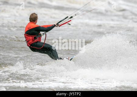 Southport, Merseyside, 19 agosto 2017. Regno Unito Meteo. Davvero un ventoso e molto più freddo giorno con alcuni pesanti Scattered Showers non scoraggiare questo kite boarder da equitazione il surf sulla marea a Southport nel Merseyside. Credito: Cernan Elias/Alamy Live News Foto Stock