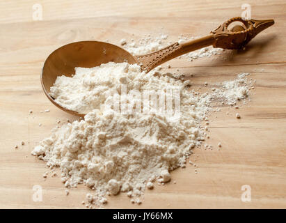 Il vecchio legno intagliato cucchiaio con farina di grano sul tavolo della cucina Foto Stock