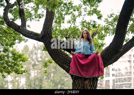 Bella ragazza giovane meditando in estate park Foto Stock