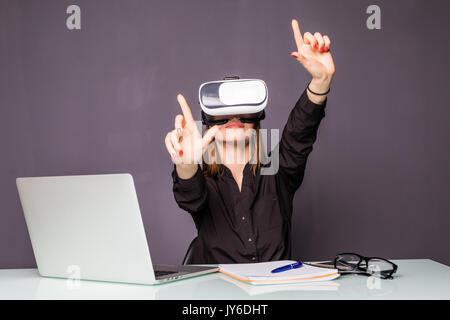 Donna in cuffia VR toccando oggetti in realtà virtuale. Ragazza seduta in poltrona alla scrivania e di interagire con la visualizzazione 3d. Foto Stock