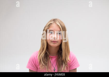 Ritratto di una poppa molto gravi e poco adorabile ragazza su una t-shirt rosa su sfondo bianco Foto Stock