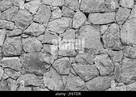 Il vecchio muro di cinta in una fortezza fatta di pietre con il lichen in bianco e nero. Foto Stock