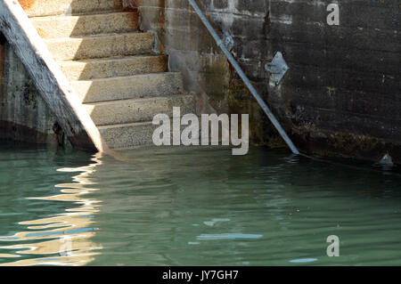 Un set di scale o gradini o dall'acqua in porto con un corrimano ad alta marea camminando nell'acqua wet Foto Stock