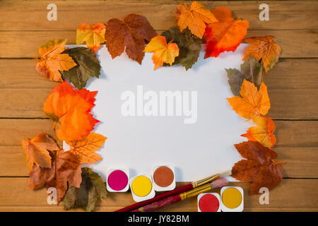 Foglie di autunno su carta con acquarello di vernice sul tavolo di legno Foto Stock