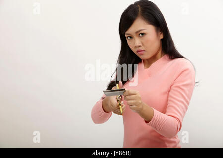 Asian tenendo un paio di forbici da taglio carta di credito Foto Stock