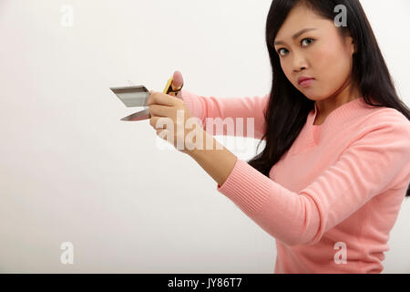 Asian tenendo un paio di forbici da taglio carta di credito Foto Stock