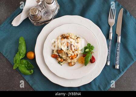 Risotto con le cozze su una piastra bianca con basilico, pomodori ciliegia su un panno verde. Mangiare sano concetto, Meditarranian stile di vita Foto Stock