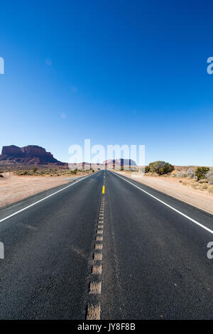 Utah, Stati Uniti d'America. Autostrada a doppia corsia di marcia che si estende verso l'orizzonte con Monument Valley nel lontano sullo sfondo. Foto Stock