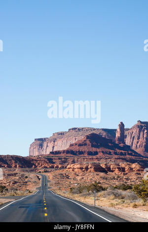 Utah, Stati Uniti d'America. Autostrada a doppia corsia di marcia che si estende verso l'orizzonte con Monument Valley nel lontano sullo sfondo. Foto Stock