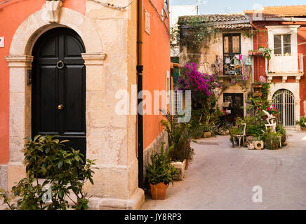 Pareti in terracotta, porta e piante in vaso in un piccolo cortile su isola di Ortigia, Siracusa, Sicilia, Italia Foto Stock