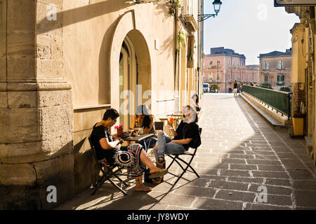 Tre giovani con aperitivi in un oudoor cafe sull isola di Ortigia Siracusa, Sicilia, Italia Foto Stock