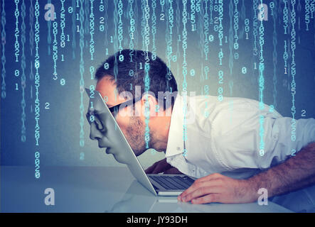 Profilo laterale di un giovane uomo di affari con la sua faccia passare attraverso lo schermo di un computer portatile sul codice binario sfondo Foto Stock
