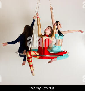 Giovane donna di trio facendo som acrobatici volteggi sull'antenna di lucentezza Foto Stock