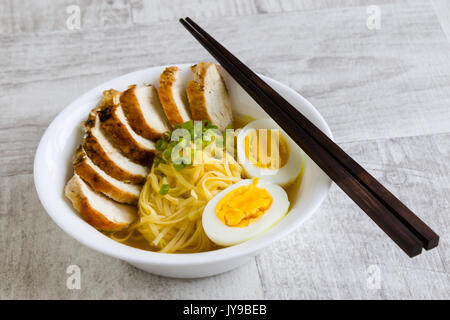Giapponese ramen zuppa di pollo e uovo sodo in ciotola bianco Foto Stock