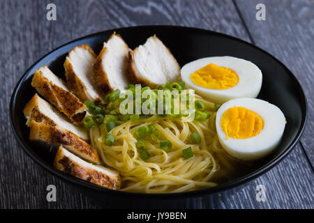 Giapponese ramen zuppa di pollo e uova sode o nel vaso nero Foto Stock