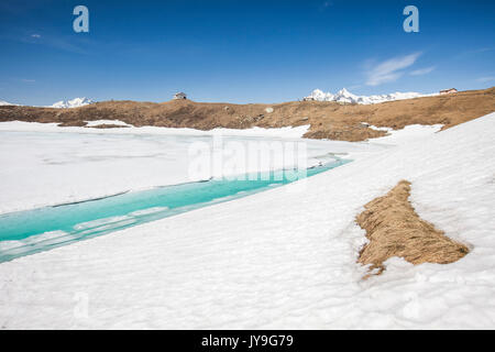 Acque turchesi del Lago Emet circondato da neve durante il disgelo di primavera Valle Spluga Sondrio Valtellina Lombardia Italia Europa Foto Stock