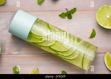 Detox infuso con acqua di calce e menta in bottiglia Sport, con fettine di lime. Foto Stock