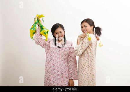 Due donna malay indossando baju kedah holding ketupat sullo sfondo bianco Foto Stock