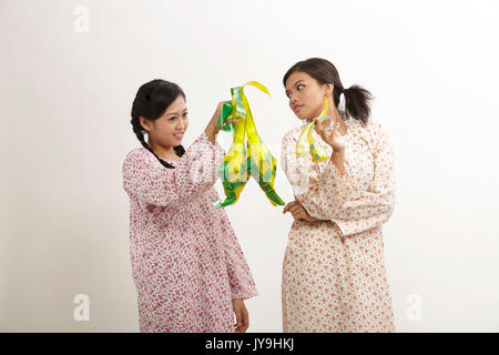 Due donna malay indossando baju kedah holding ketupat sullo sfondo bianco Foto Stock