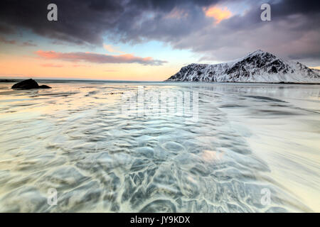 Onde il surreale Skagsanden spiaggia circondata da montagne coperte di neve. Isole Lofoten Norvegia del Nord Europa Foto Stock