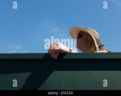 Donna che indossa cappello di paglia guardando oltre il recinto a campionati di Wimbledon 2017, Londra, Gran Bretagna, Regno Unito. Foto Stock