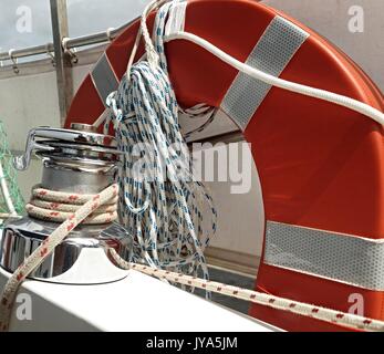 Immagine nautico di ingranaggio in barca sul ponte di uno yacht tra cui una velocità di due deck verricello, salvagente e fascio di corda closeup. Foto Stock