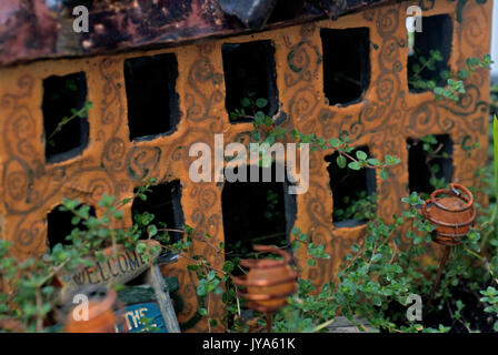 Giallo in ceramica casa di fata in un giardino alberato Foto Stock