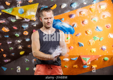 Rocciatore mettendo chalk su mani in piscina palestra di arrampicata Foto Stock