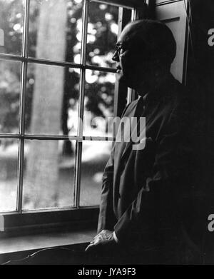 Milton stover eisenhower, presidente della Johns Hopkins University, in piedi e guardando fuori da una finestra, 13 giugno 1963. Foto Stock