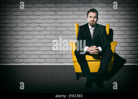Bello imprenditore solo seduta sulla poltrona nella stanza vuota. imprenditore seduto da solo spazio copia banner web concept Foto Stock