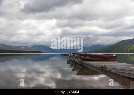 Categoria : Barche sul molo con mountain-gamma background e simili a specchio Lago McDonald con riflessioni di Cloud Foto Stock